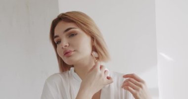 Mükemmel, pürüzsüz, sağlıklı cilde sahip güzel bir kadın yeşil yüz silindiri kullanarak masaj yaptırıyor. Evde güzellik tedavisi. Dermatoloji aletiyle cildine masaj yapan bir kadın. Sabah güzellik ayinleri.