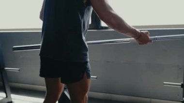 Modern bir spor salonunda halter kaldıran bir adam. Büyük pencerelerden içeri doğal ışık süzülüyor. Güç, zindelik ve kararlılığa odaklan. Modern Spor Salonunda Halter Kaldıran Adam