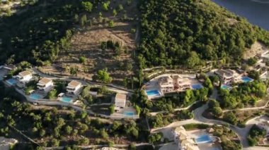 Aerial Upward Shot Of Luxurious Villas with large pool Amidst Green Trees On Mountains. Modern house in a mountain forest. Home exterior with forest. Luxury house in forest.