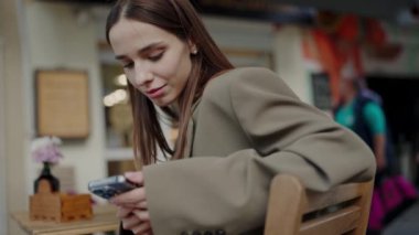 Odaklanmış genç bir kadın, bir kafede oturuyor, akıllı telefonuna dalmış, bulanık bir geçmişi olan, şehir yaşamını gözler önüne seriyor. Kafe 'de Akıllı Telefon Kullanan Genç Kadın, Teknolojiye daldı