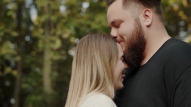 Genç, sevecen bir çiftin açık hava ortamında kucaklaşması ve gülümsemesi. Görüntü huzurlu ve sevgi dolu bir anı yakalar. Açık havada Neşeli Bir Anı Paylaşan Genç Çift