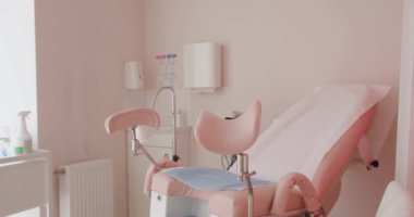 Pembe dekor ve modern tıbbi ekipmanlarla aydınlık bir jinekoloji muayene odası, temiz ve misafirperver bir sağlık ortamı sunuyor. Klinikteki Modern Pembe Jinekoloji Muayene Odası