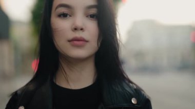 Koyu saçlı bir kadının yakın plan portresi şehir ortamında bulanık arka planda dikiliyor. Kentsel Ayarlarda Siyah Saçlı Genç Kadın Portresi