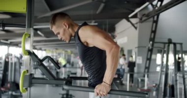 Motive olmuş atletik erkek, kas gücünü ve vücut şeklini arttırmak için spor aletleri kullanıyor. Modern Spor Salonu 'nda Yoğun Fiziksel Antrenman Yapan Genç Adam