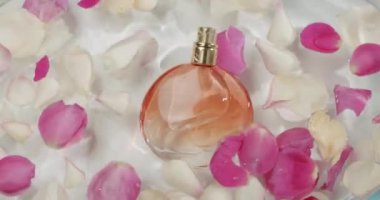 Narin, pembe ve beyaz gül yapraklarıyla çevrili, suyun içinde dinlenen zarif, yuvarlak bir parfüm şişesi. Sahne tazelik, romantizm ve lüks hissi uyandırıyor. Zarif Parfüm Şişe