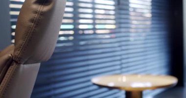 Rahat çalışma odasında minimalist deri koltuklu modern ahşap çalışma masası. Oda palmiyesi dekoru. Minimalist siyah panjurlar. Beauty Interior 'da yatak odası aksesuarı, deri koltuk ve modern masa..