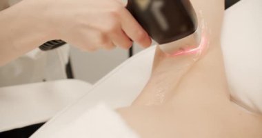 Güzellik uzmanı, güzel kadın koltuk altlarındaki kılları lazerle alıyor. Güzellik salonunda bacaklarındaki kılların donanımlı bir şekilde alınması. Lazer epilasyon kozmetolojisi. Saç çıkarma prosedürü, lazer epilasyonu..