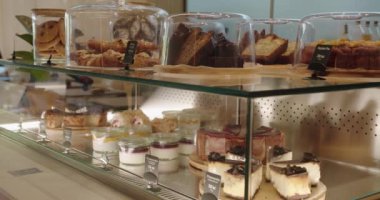 Bir kafe ortamında çeşitli tatlıların cazip bir görüntüsü açık kapaklı cheesecakes, turtalar ve hamur işleri içerir.