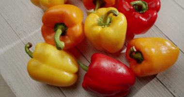 Ahşap bir yüzeye kırmızı, sarı ve turuncu renkli dolmalık biberler serpiştirmek ve beslenme ihtiyaçları için ideal sağlıklı ve canlı bir çeşitlilik sergiliyor. Canlı Taze Sebzeler
