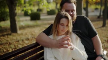 Parktaki bankta oturan genç bir çift, birbirine dolanmış eller ve huzurlu, samimi bir anın tadını çıkarıyorlar. Batan güneş, sevgiyi ve birlikteliği vurgulayan sıcak bir parıltı ekler. Samimi Çift