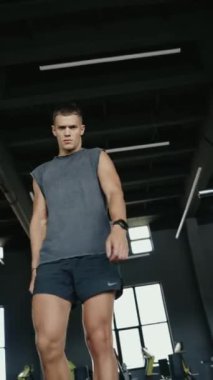 Spor salonunda çalışan motive olmuş bir adamın yakın çekimi. Yoğun bir çalışma sırasında gücünü ve kararlılığını gösteriyor. Motivasyonlu Adam Spor Salonu Güç Gösterisinde çalışıyor. Dikey