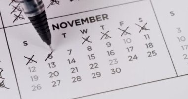 Zaman yönetimi, planlama ve programları temsil eden, üzeri çizilmiş tarihler ve belirli bir günü işaretleyen bir Kasım takviminin kapatılması.