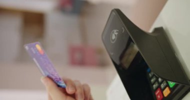 Kredi kartı tutan müşterilerin yakın çekim görüntüsü, bir mağazanın içinde ödeme için bir satış terminali kullanıyor. Mağazadaki Satış Terminalinde Müşteri Kredi Kartı Kullanıyor. Dikey video.