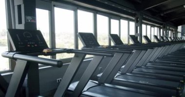 Geniş pencereli manzaralı modern bir spor salonunda yüksek teknoloji koşu bantları. Spor meraklıları için mükemmel. Modern Spor Salonu Koşu Değirmenleri Güneşli Manzaraya Bakıyor