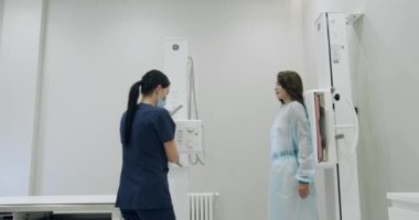 Machine while Female Doctor Adjusts it. Healthy Patient Undergoes Routine Scanning with the Nurses Help.