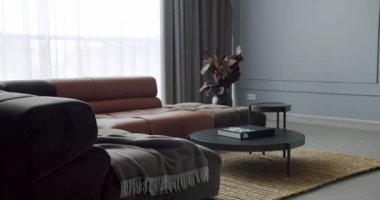 Gri ve kahverengi mobilyalı modern Minimalist oturma odası. Köşedeki kanepe ve yuvarlak masalı lüks Modern Ev İçi. Moda mobilyalar. Minimalist Ev İçi.