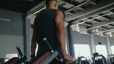 Sporcu, geniş ve modern bir spor salonunda göğüs pres makinesinde egzersiz yapıyor. Güç antrenmanına odaklanıyor. Modern Spor Salonu 'nda Göğüs Baskısı Makinesinde Sporcu Egzersizi