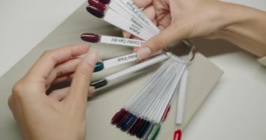 Müşteri için çok renkli oje paleti. Manikür için tırnak cilası örnekleri. Güzellik salonunda renkli bir manikür paleti. Oje örnekleriyle birlikte palet.