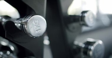 Spor salonundaki dambılların detaylarını gösteren, metalik dokulara ve ağırlıklara odaklanmış yakın plan bir görüntü. Fitness ve egzersiz temaları için ideal.