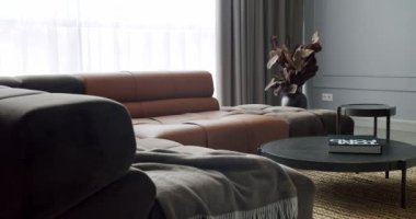 Gri ve kahverengi mobilyalı modern Minimalist oturma odası. Köşedeki kanepe ve yuvarlak masalı lüks Modern Ev İçi. Moda mobilyalar. Konforlu Modern Mobilya Tasarımı.