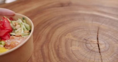 Poke kasesi, geleneksel Hawaii çiğ balık salatası. Somon, pirinç, avokado, edamame fasulyesi, ahşap zemin üzerinde salatalık. Sağlıklı yemek, keto diyeti konsepti. Asya çiğ yemeği.