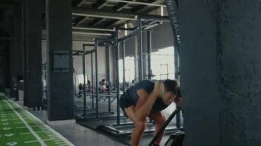 Modern bir spor salonunda çalışan genç bir adam. Çeşitli fitness ekipmanlarıyla dolu. Spor salonu geniş ve aydınlık, sağlıklı ve aktif bir yaşam tarzını destekliyor. Spor salonunda egzersiz yapan genç adam.