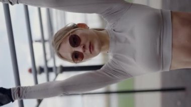 Atletizmde odaklanmış genç bir kadın açık havada yatay bir barda esneyerek kendini adamış ve formda görünüyor. Esneme Egzersizinde Atletik Kadın Açık havada