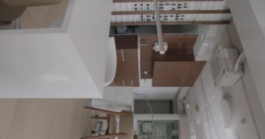 Masalar, sandalyeler ve ofis ekipmanlarının yer aldığı temiz ve modern bir ofis ortamının ilgi çekici bir hava görüntüsü. Dikey video.