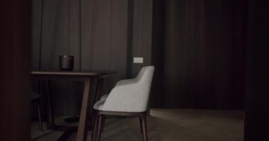 Modern bir minimalist yemek odası şık gri sandalyeler ve koyu ahşap dekorlarla zarif ve rahat bir atmosfer yaratıyor. Ev ayarları ve iç tasarım ilhamı için mükemmel.