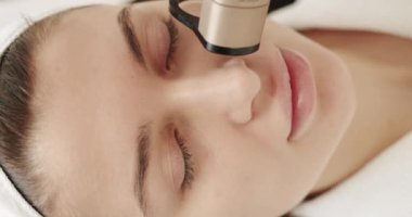 Kadın güzellik kliniğinde LPG donanım masajı yaptırıyor. Bir tıp merkezinde lazer yüz tedavisi gören genç bir kıza yakın çekim, cilt tazeleme konsepti. Güzellik tedavisi.