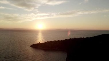 Denizden yükselen güneş. Renkli bulutlu gökyüzü ve güneş ışınları. Sakin denizin üzerinde gün doğumu. Güneş denizin tam üstünden doğar ve suyun yüzeyine büyük ve güzel bir ışık yansıtır..