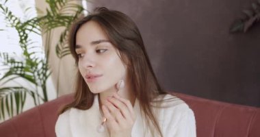 Mükemmel, pürüzsüz, sağlıklı cilde sahip güzel bir kadın yeşil yüz silindiri kullanarak masaj yaptırıyor. Evde bakım kavramı. Yüz bakımı ve güzellik ayinleri. Evde güzellik tedavisi..