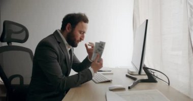 İş adamı nakit para, dolar, maaş ve iş yerindeki kazançları sayıyor. Takım elbiseli tatmin olmuş patron kârı sayıyor. Yakışıklı mutlu iş adamı dolarları dağıtıyor..