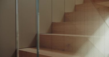 İnce ve samimi bir çekim çıplak ayakları yakalıyor ahşap merdivenlerden tırmanıyor, pencereye doğru hafif bir güneş ışığıyla aydınlatılıyor, sıcak, sıcak bir atmosfer yaratıyor. Yalınayak Tahta Merdivenlere tırmanan Kişi