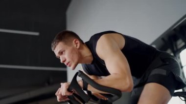 Spor salonundaki genç, zinde bir adam TRX bantlarıyla takılır, modern bir spor salonunda azim ve kararlılıkla antrenmanına odaklanır. Genç Adam TRX bantları kullanarak Yoğun Spor Salonu Çalışmasına Odaklandı