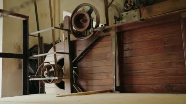 Atölyede ahşap ve metal parçaları olan eski bir endüstriyel makinenin yakın görüntüsü. Mekanizma, eski, kırsal ve karmaşık tasarımı vurgulayarak ayrıntılı olarak gösterilir..