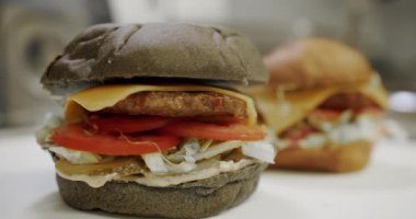 Hamburger pişiriyorum. Lezzetli hamburger yemeye hazır. Lezzetli fast food konsepti. Yakın plan. Köfteli hamburger, domates, salatalık, marul. Restoran Mutfağında Yemek Pişirmek.