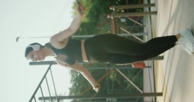 İspanyol kadın kardiyo yapıyor ve parka atlıyor. Genç bir kadın spor sahasında ip atlıyor. Ağır çekim. Fitness eğitimi ve vücut bakımı konsepti. İp atlıyorum. Dikey video.