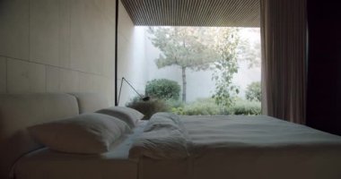 Bu resim, huzur ve modern tasarımı vurgulayan yemyeşil bir bahçe manzaralı huzurlu bir yatak odası sahnesini yakalıyor. Çağdaş Yatak Odası Bereketli Yeşillik Bahçesine Bakar