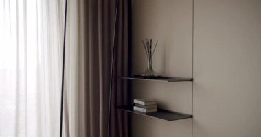 Kitaplığı, dekoratif eşyaları, perdeleri ve televizyonu olan minimalist bir tasarımı sergileyen çağdaş bir yaşam alanı. Perdeleri, Kitaplığı ve Minimal Dekoru olan Modern İçmimari