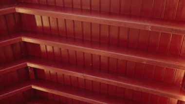 Geometrik desenli kırmızı ahşap tavanın soyut yakın plan görüntüsü ışık ve gölgeleri yakalıyor. Mimari ve tasarım temaları için mükemmel.