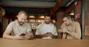 Çevredeki akıllı telefonlara bilinçsizce bakıyorum. Çok ırklı bir grup insan akıllı telefonlarını aktif olarak kullanıyor. Bir kafede telefon kullanan üç arkadaş..