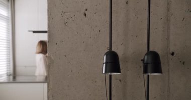 Modern bir mutfak odasında, minimalist bir dairede, beyaz bir evde, beton ve konforlu donanımlı gri renkli bir evde bir kadın kahve yapıyor. modern tasarım ve dekorasyona sahip ev aletleri.