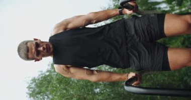 Atletik adam spor yapar, dışarıda paralel barlarda takılır ve durur. Parktaki spor alanında spor yapan kaslı vücutlu genç bir erkek. Yatay Çubuklar Üzerine Barfiks Egzersizi Yapan Sporcu
