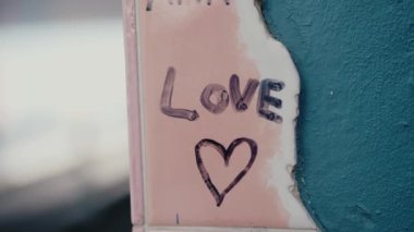 Kırık bir duvarda kalbi olan aşk grafitisinin yakın çekimi. Görüntü, hasara rağmen sevgi, şehir sanatı ve aşkın devamlılığı mesajlarını iletiyor. Duvarda aşk mesajı ve kalp resmi var.