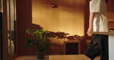 Bu resim, şık ahşap mobilyaların yanında güneş ışığıyla yıkanmış bir saksı bitkisinin sergilendiği huzurlu ve modern bir iç mekanı gösteriyor. Doğal ışıklandırma, sakin ve davetkar atmosferi vurgular.