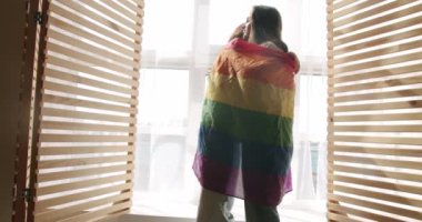 Çift, Lgbt ve lezbiyen kadınlar evde. Sarılın, gülümseyin ve bayrak sallayın. Sevgilerle, LGBTQI. Lezbiyen çiftin aşk ve portresi. LGBT hakları, lezbiyen ailesi.