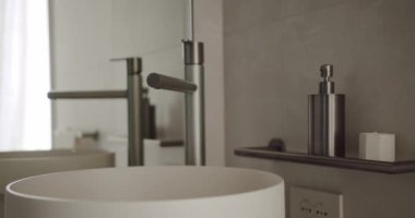 Çağdaş minimalist bir banyo, parlak krom bir musluk, beyaz bir damar lavabosu ve uygun bir sabunluk, temizlik ve sofistike hissi uyandırıyor. Modern Minimalist Banyo İçi