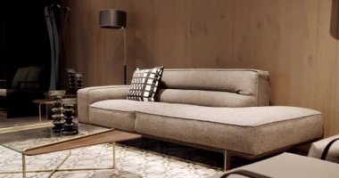 Modern gri ve bej kumaş kanepe. Yastıklı tekstil döşeme kanepesi. Modern apartman güzel bej kanepe modern oturma odasında lamba, halı, masa. Ahşap duvarlı İskandinav iç mimarisi