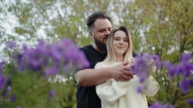 Romantik bir çift, çiçek açan, sevgi ve şefkat gösteren, huzurlu bir bahçe ortamında kucaklaşır. Çiçek açan bir bahçede kucaklaşan romantik çift, Sevgi ve şefkat